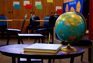 A globe placed on a table in an empty classroom, with chairs arranged around it.
